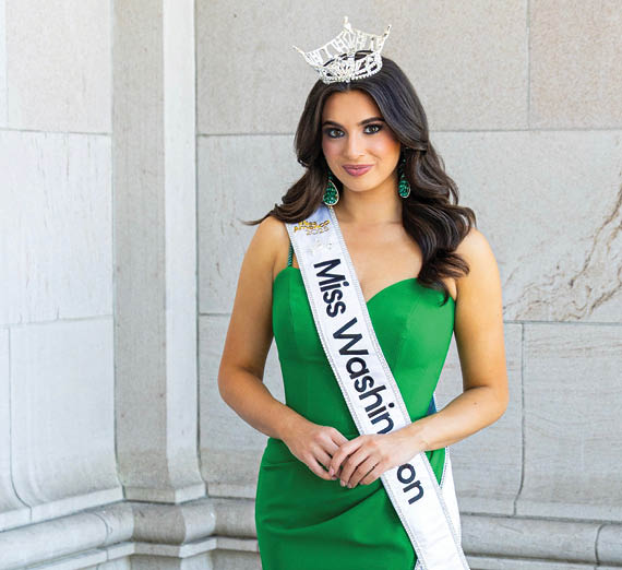 Man leans against brick wall with cherry blossom tree behind it.