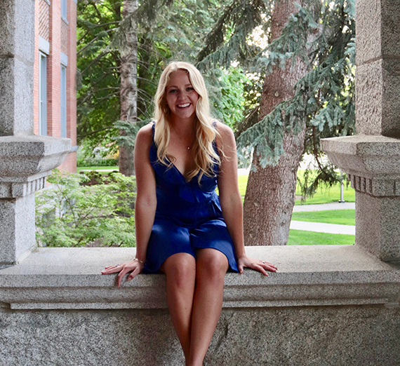 Una mujer está de pie con los brazos cruzados junto a una ventana.